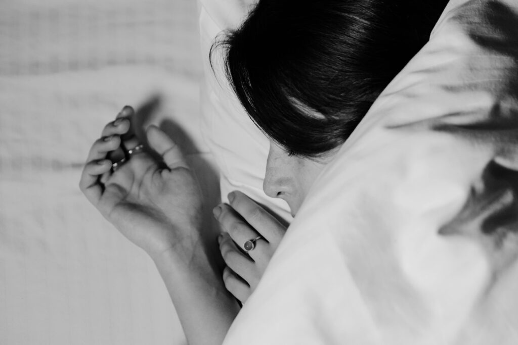 A close-up black and white photo capturing a peaceful sleeping person with delicate hand poses.